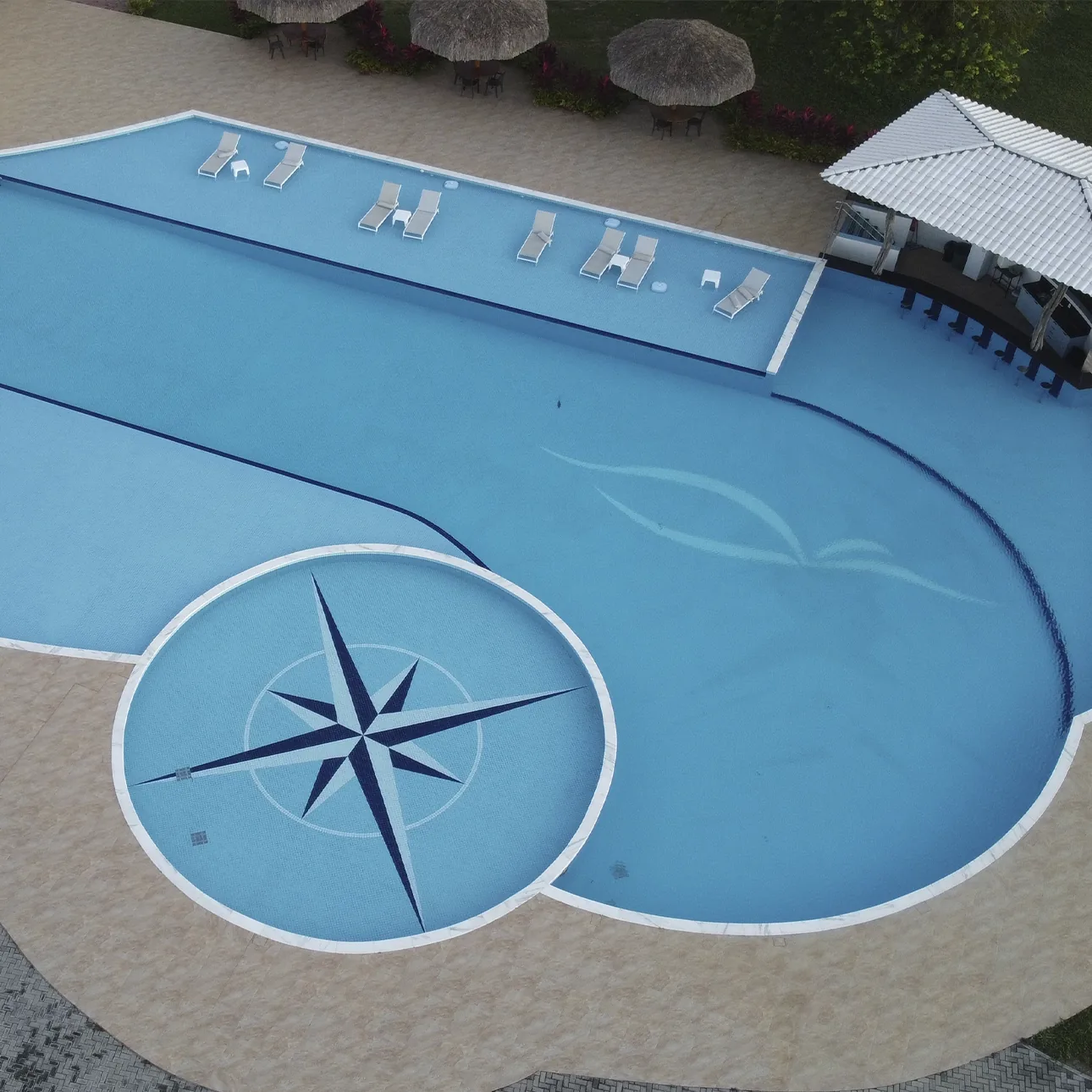 Vista aérea da piscina do condomínio com rosa dos ventos no fundo